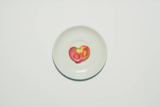 istock Minimal heart shaped tomato slice background. Fruit on white plate. 700313594