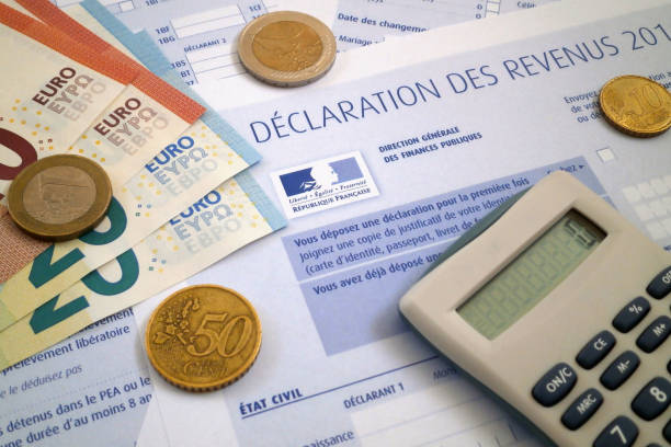 French income tax form A calculator and some euro coins and banknotes on the top of a french income tax form. european union coin photos stock pictures, royalty-free photos & images