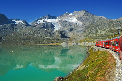 red train in the Swiss mountains in summer