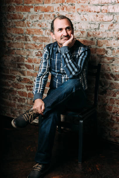 istock Handsome middle aged man is dressed in a casual clothing. Red brick wall background. 700333040