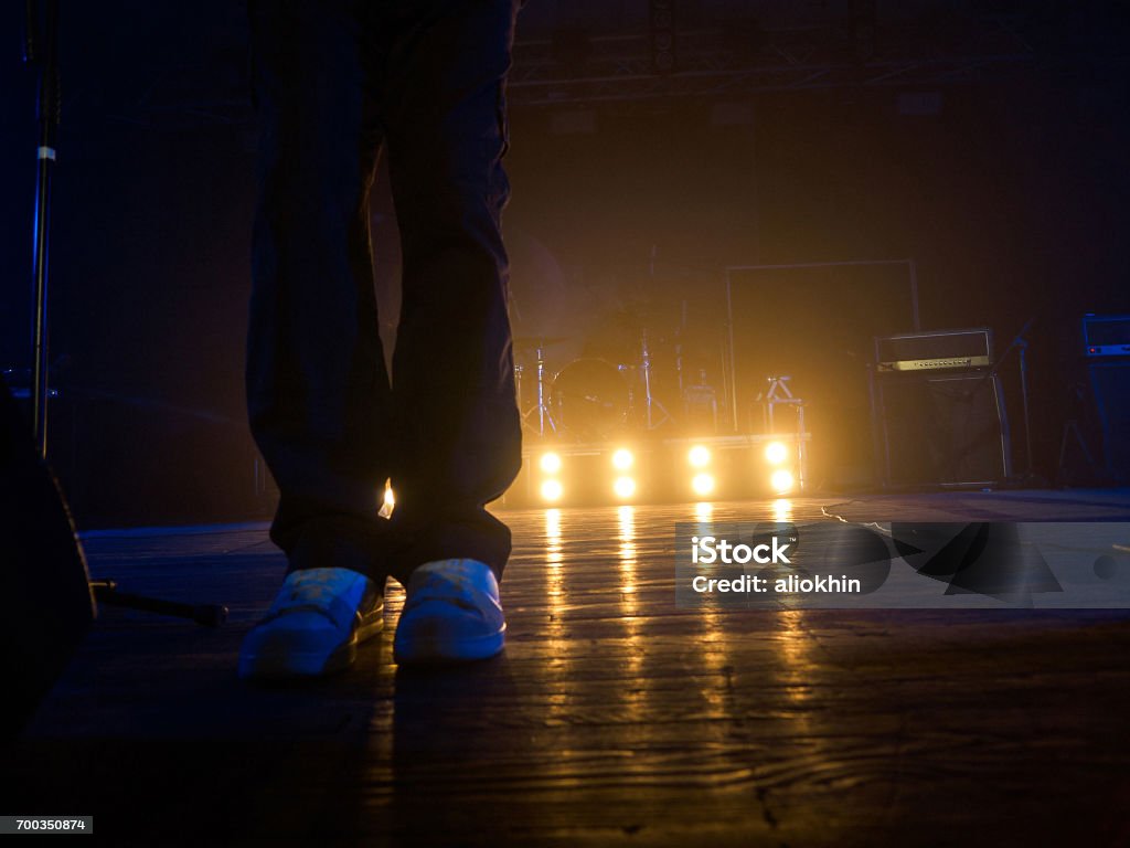 Legs on the concert stage Musician legs in white sport shoes on the stage with spotlights, acoustic systems and drum set on the background Foot Stock Photo