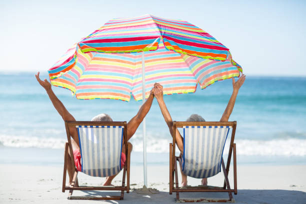 istock Cute mature couple raising arms on deckchairs 700366642