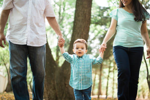 istock Little boy holding hands with parents and looking at camera 700373076