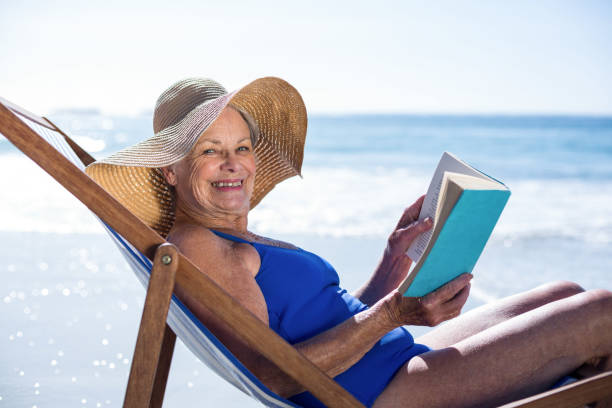 istock Pretty mature woman reading a book lying on deck chair 700373188