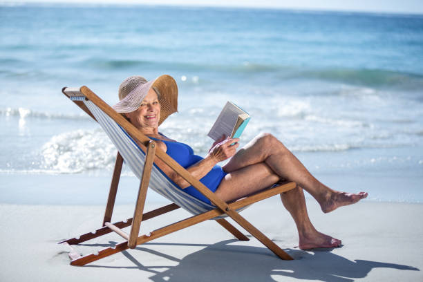 istock Pretty mature woman reading a book lying on deck chair 700373302