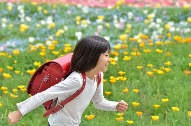 istock Girl running in flower garden (school bag) 700382482