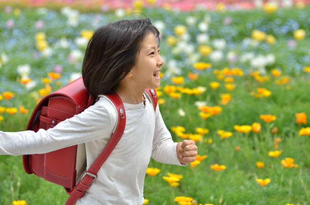 Girl running in flower garden (school bag)