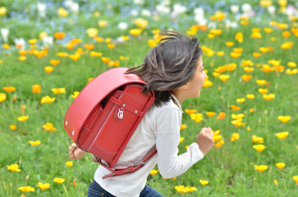 Girl running in flower garden (school bag) Girl running in flower garden (school bag) randoseru stock pictures, royalty-free photos & images