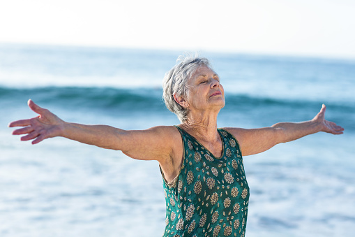Senior woman outstretching arms at the beach