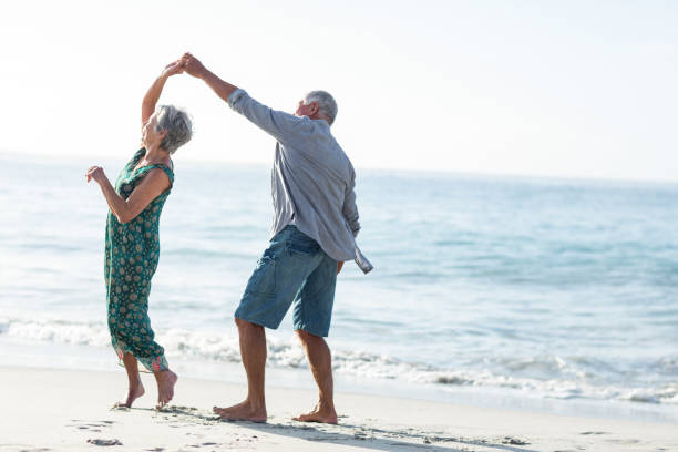 älteres paar tanzen am strand - senior couple stock-fotos und bilder