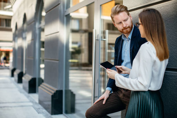 istock Two business people using digital tablet outdoors 700408424