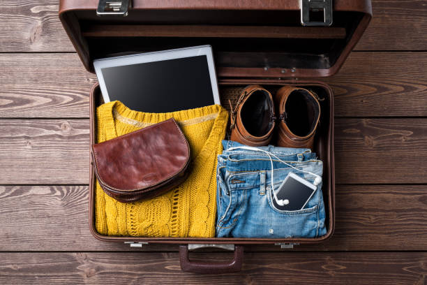 istock Open suitcase with casual female winter clothes on wooden table. 700414996