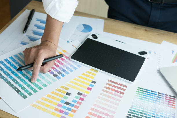 istock young graphic designer working with computer and color swatch. creative man using stylus pen and digital tablet at modern office. Architect using work tools and sample colour catalog. business, technology, design and people concept 700451136