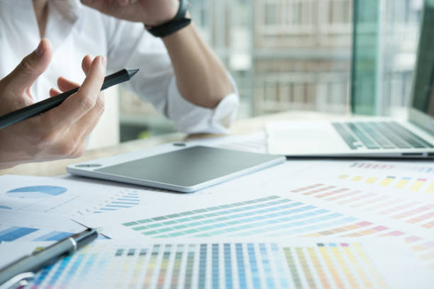 istock young graphic designer working with computer and color swatch. creative man using stylus pen and digital tablet at modern office. Architect using work tools and sample colour catalog. business, technology, design and people concept 700451182