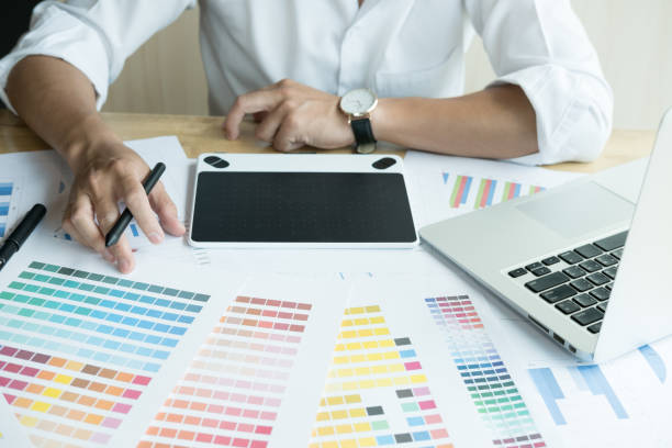 istock young graphic designer working with computer and color swatch. creative man using stylus pen and digital tablet at modern office. Architect using work tools and sample colour catalog. business, technology, design and people concept 700451196