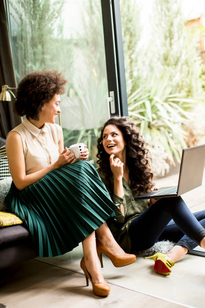 istock White and african american  women sit at home and using laptop 700473260