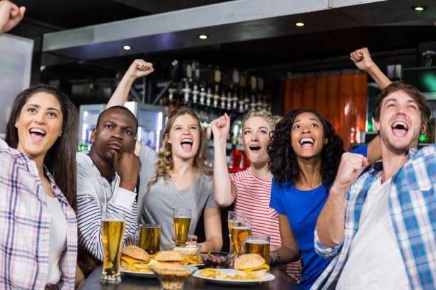 Happy friends having a drink and watching sport