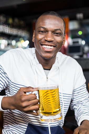 Portrait of smiling man drinking a beer in a bar