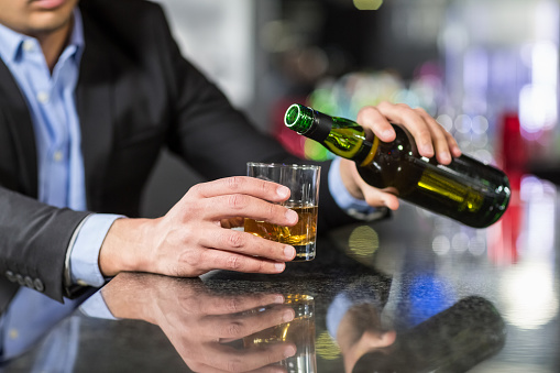Businessman pouring whisky in glass in a bar