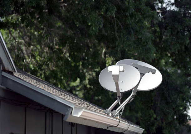 Pair of Satellite dish television tv receiver antennas on a rooftop.