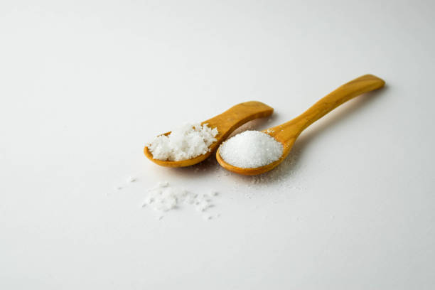 istock salt and sugar on small wooden spoon on white background 700540568