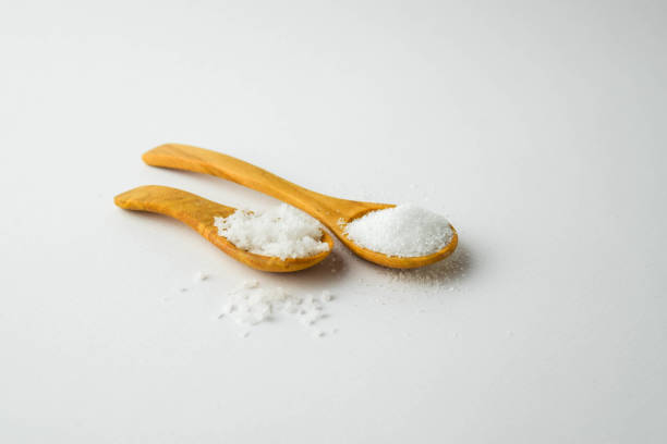 istock salt and sugar on small wooden spoon on white background 700540612