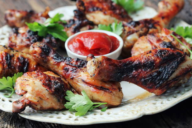 istock Grilled chicken legs on wooden table served on white plate with coriander 700563756