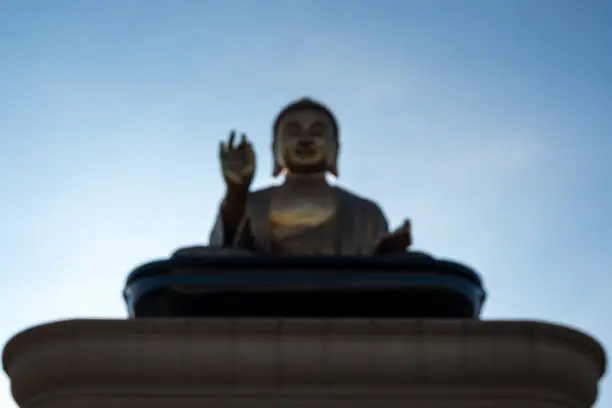 Defocused and blurred large seated Buddha on platform with blue sky in the background at Fo Guang Shan Monastery in Kaohsiung, Taiwan.