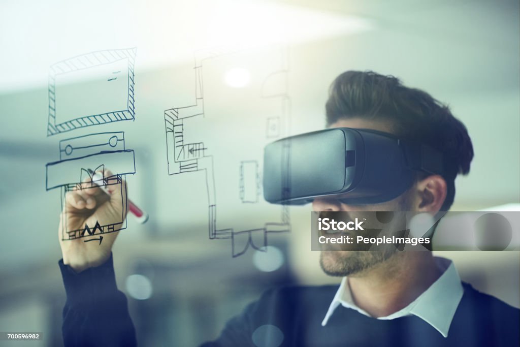 Build your own reality Shot of a businessman wearing a VR headset while drawing on a glass wall in an office Virtual Reality Simulator Stock Photo