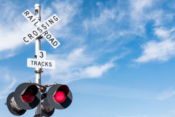 railroad crossing with wispy cloud in blue sky behind - road warning sign road sign blank safety imagens e fotografias de stock