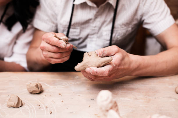 istock hands working and finishing sculpture with clay on wooden table in workshop 700609084