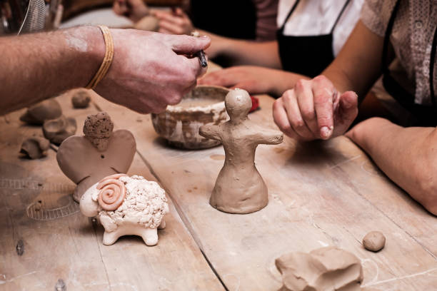 hands working and finishing sculpture with clay on wooden table in workshop