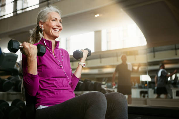 Live, laugh, love, lift Portrait of a happy senior woman working out with weights at the gym old woman stock pictures, royalty-free photos & images