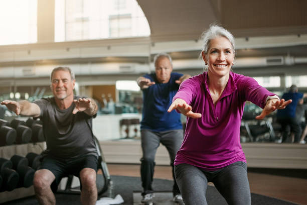 Now squat! Shot of a senior group of woman and men working out together at the gym exercise class stock pictures, royalty-free photos & images