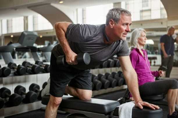 fuertes brazos ven bien a cualquier edad - máquinas de ejercicios fotografías e imágenes de stock