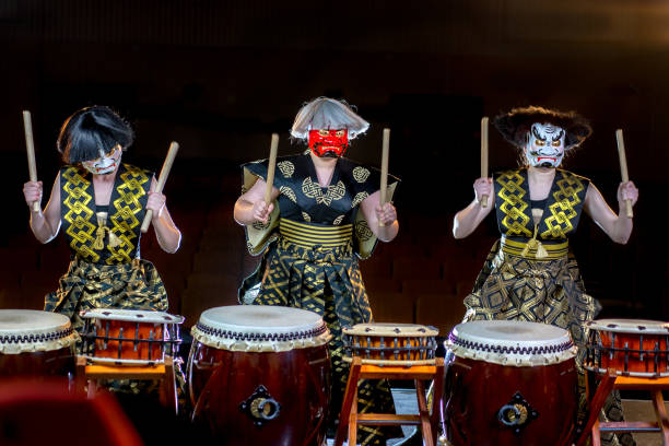 두통의 개념입니다. 백색과 빨강 악마 mesks에 세 여자 drummers 신경에 드럼 롤을 재생합니다. 스튜디오 콘서트 어두운 배경에서 촬영. - taiko drum 뉴스 사진 이미지