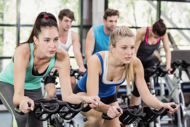 istock Fit group of people using exercise bike together 700633502