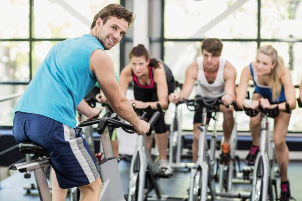 istock Fit group of people using exercise bike together 700633570