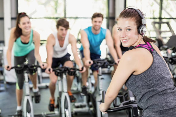 fit group of people using exercise bike together - spinning instructor exercising gym imagens e fotografias de stock