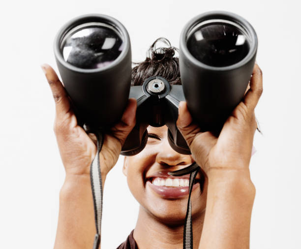 istock Smiling young woman looks at camera through binoculars 700641174
