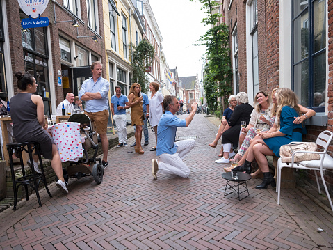 Leeuwarden, Netherlands, 11 june 2017: people enjoy themselves in narrow street in front of cafe in the centre of old city leeuwarden in friesland, cultural capital of europe in 2018