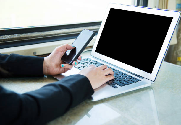Businesswoman on train using mobile phone and laptop