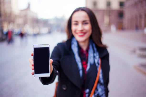 istock young woman holding smartphone 700645260