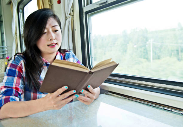 istock Young asian woman reading book on a train 700646430