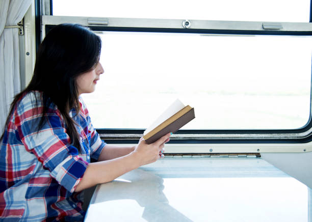 istock Young asian woman reading book on a train 700646538