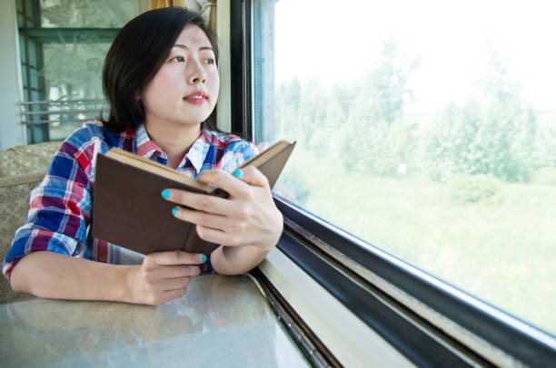 istock Young asian woman reading book on a train 700646550