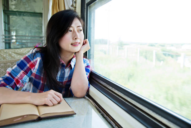 istock Young asian woman reading book on a train 700646664