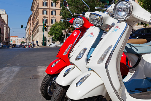 Rome, Italy - June 9, 2017: A row of white and red Vespa scooters is parked along Via Cavour, where you rent a scooter.