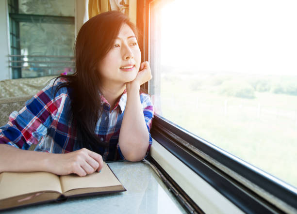 istock Young asian woman reading book on a train 700648966