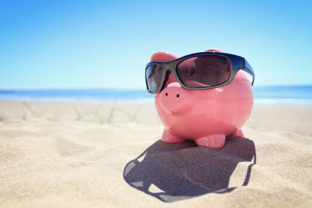 istock Summer piggy bank with sunglasses on the beach 700649718
